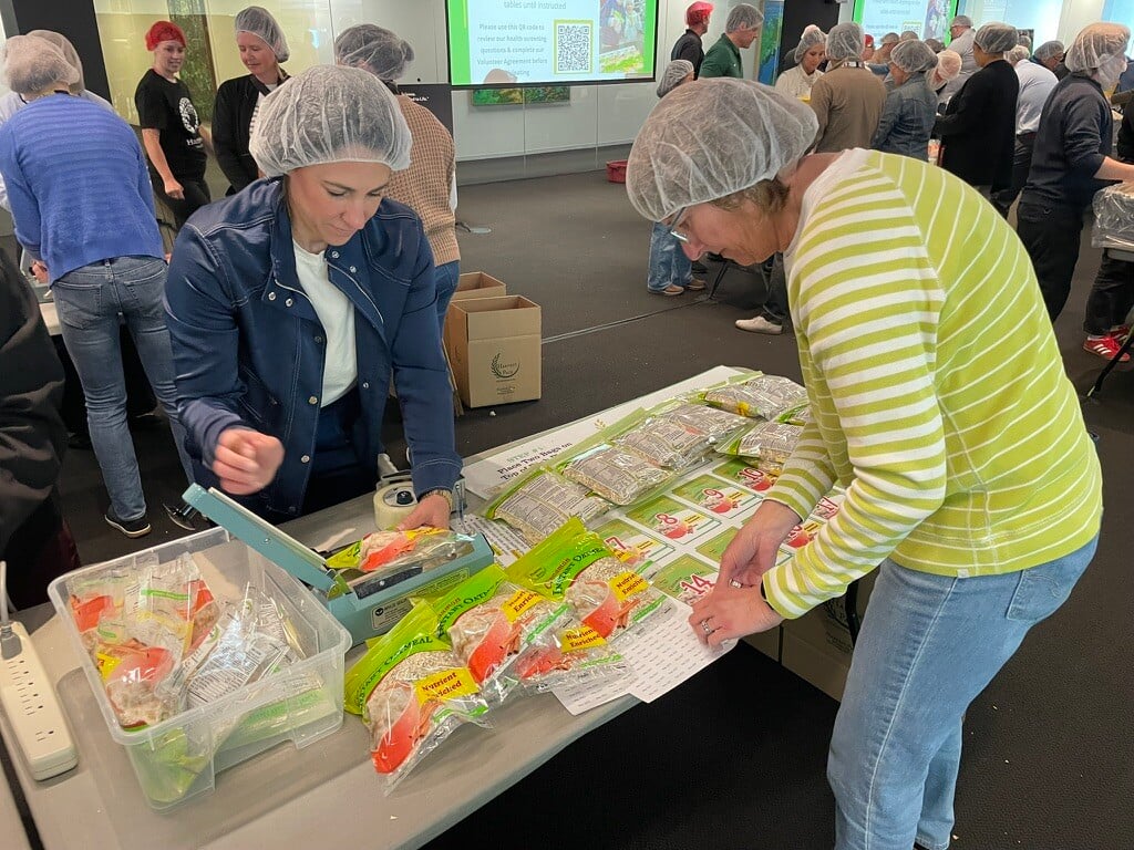 Employee volunteers sealing bags of oatmeal and filling boxes of packed oatmeal.