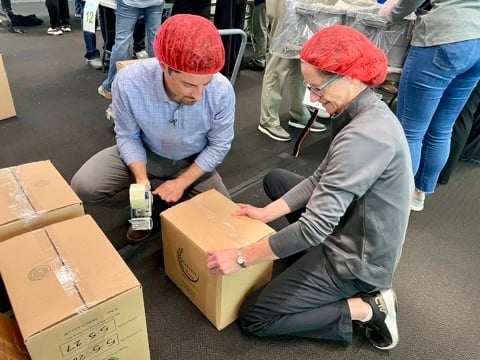 Employee volunteers boxing packed Harvest Pack meals 